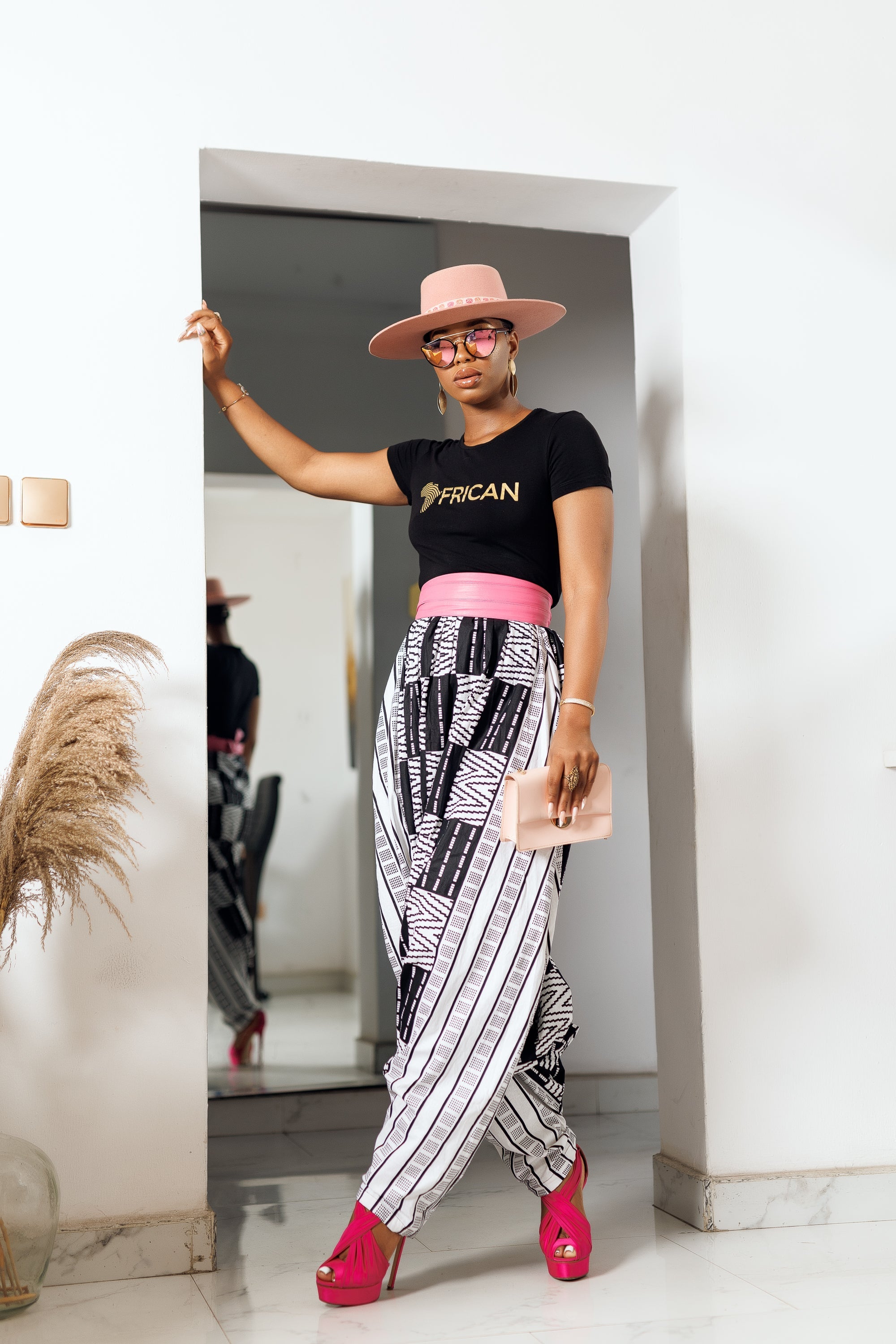 A woman posing in black and white African Print parachute pants.