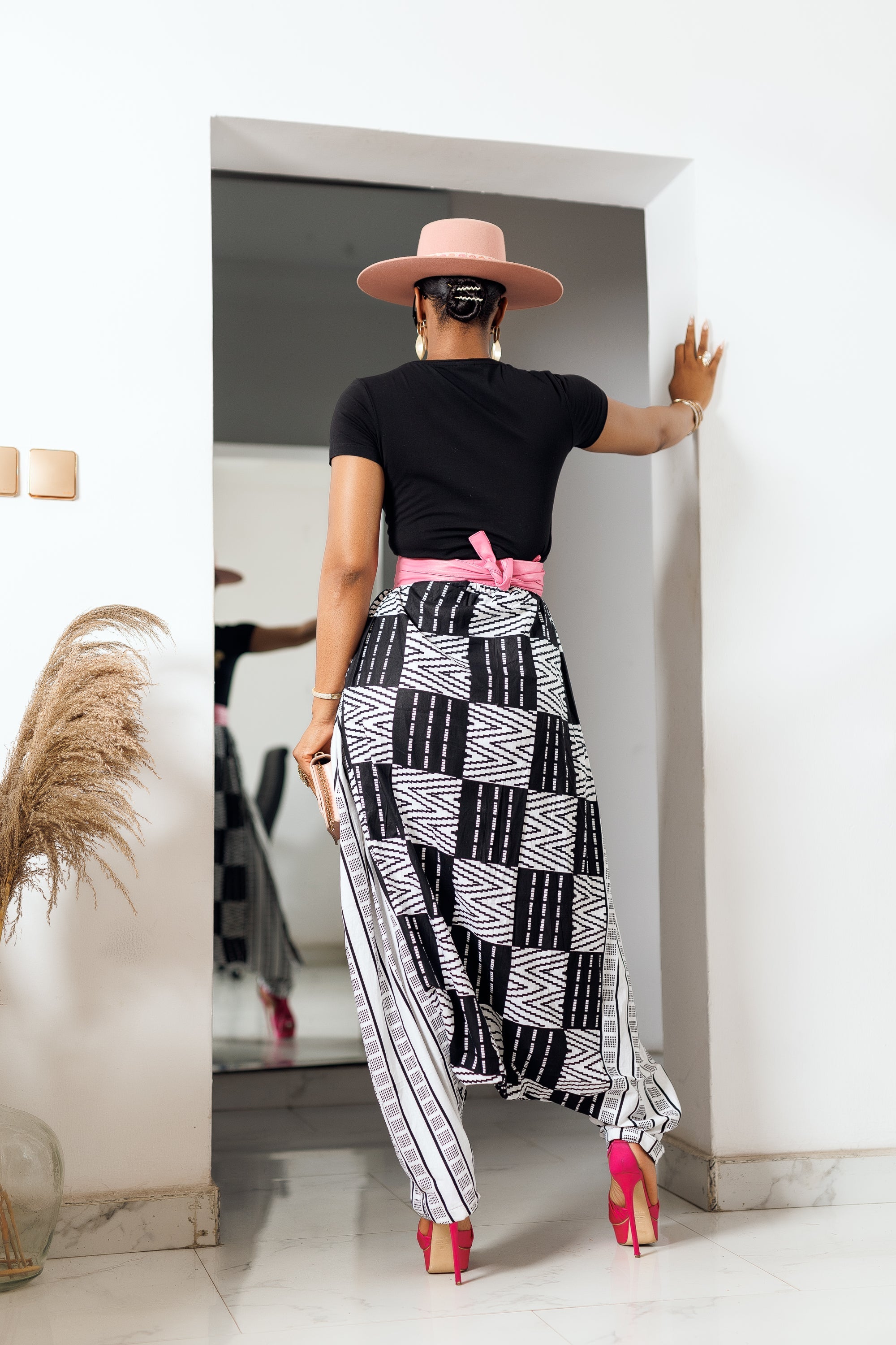 A woman posing in black and white African Print parachute pants.