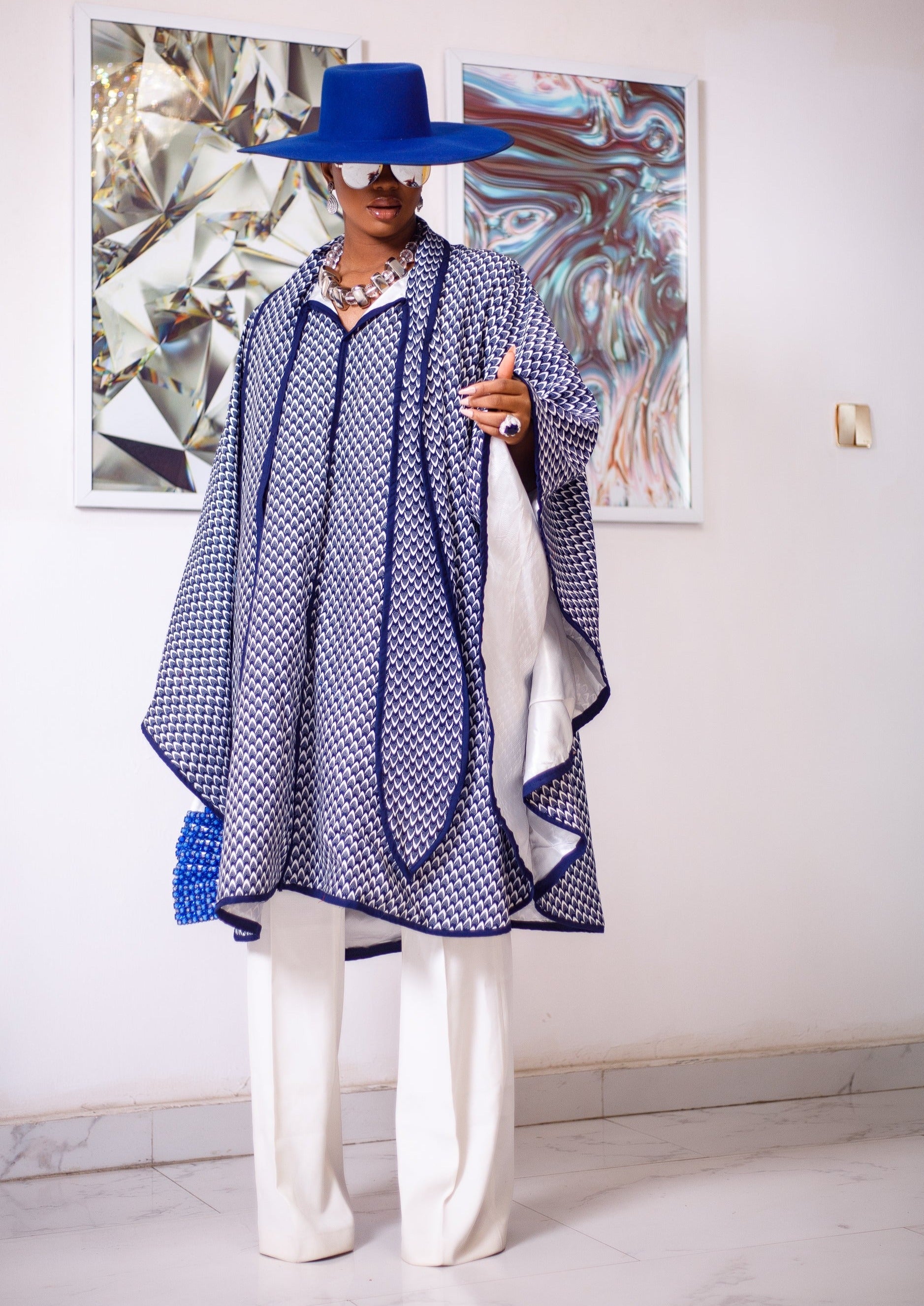 A woman posing in a blue and white African Print cape.