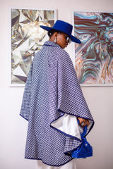 A woman posing in a blue and white African Print cape.