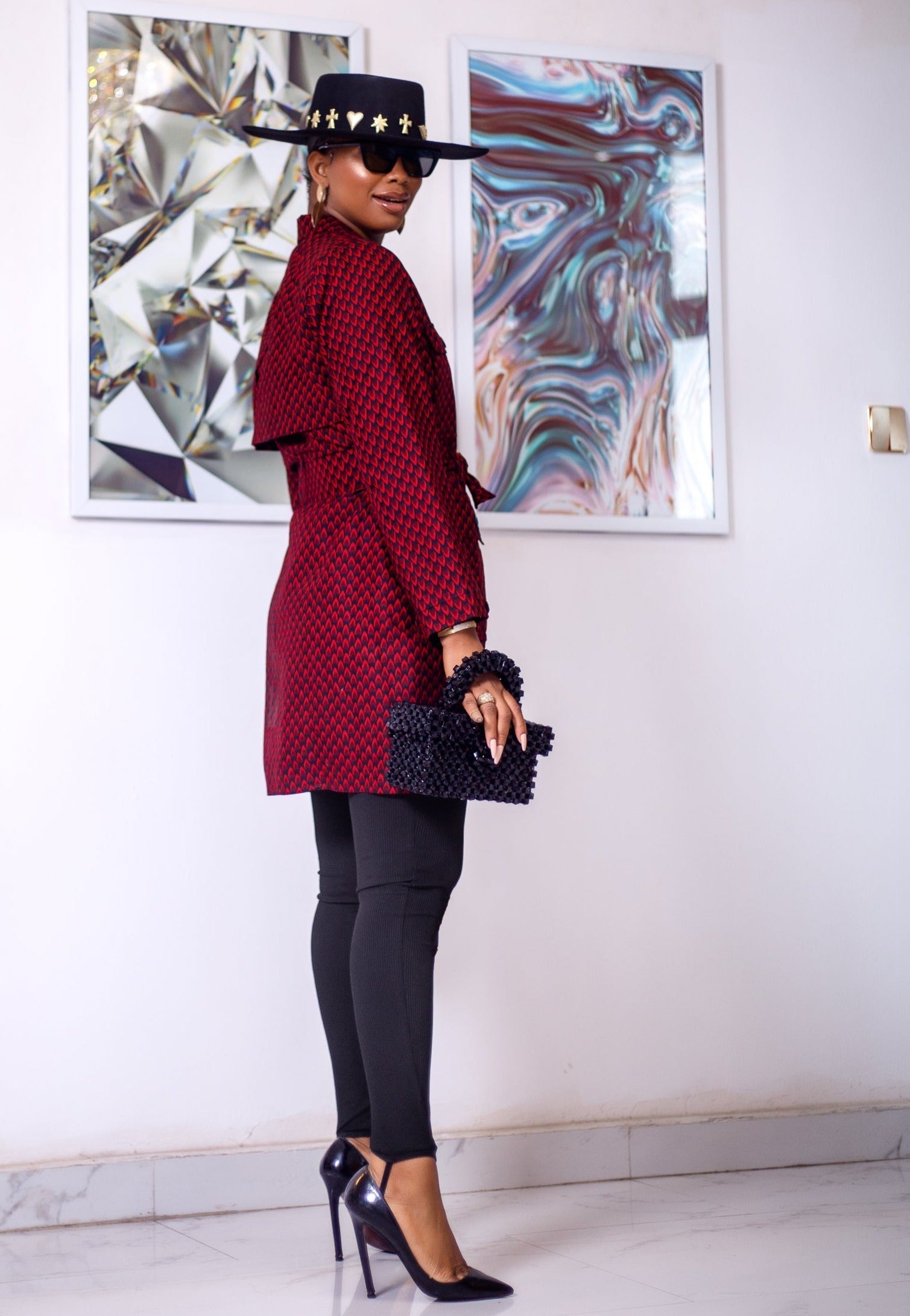 A woman posing in a black and red African print trench coat.