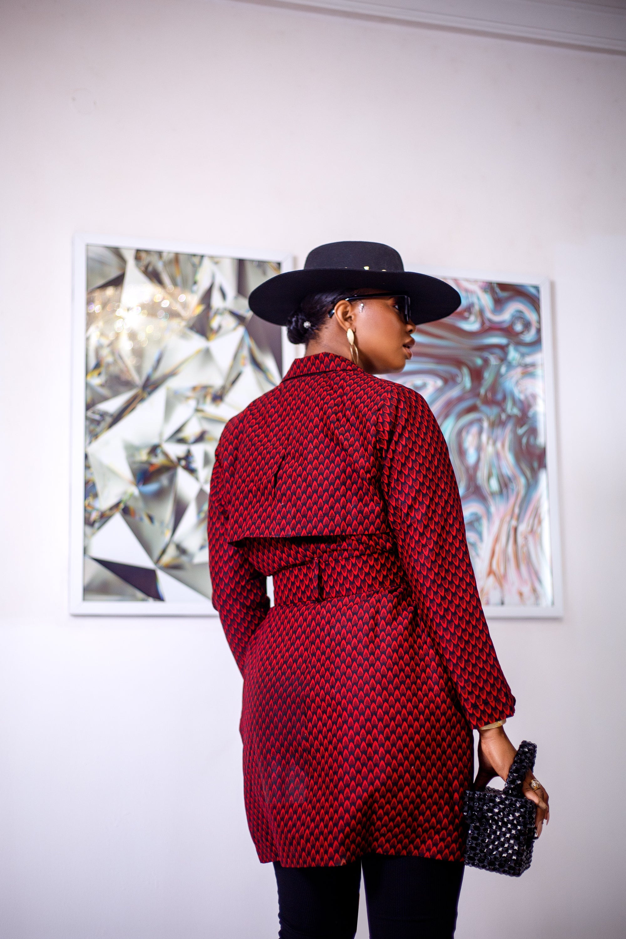A woman posing in a black and red African print trench coat.