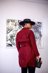 A woman posing in a black and red African print trench coat.
