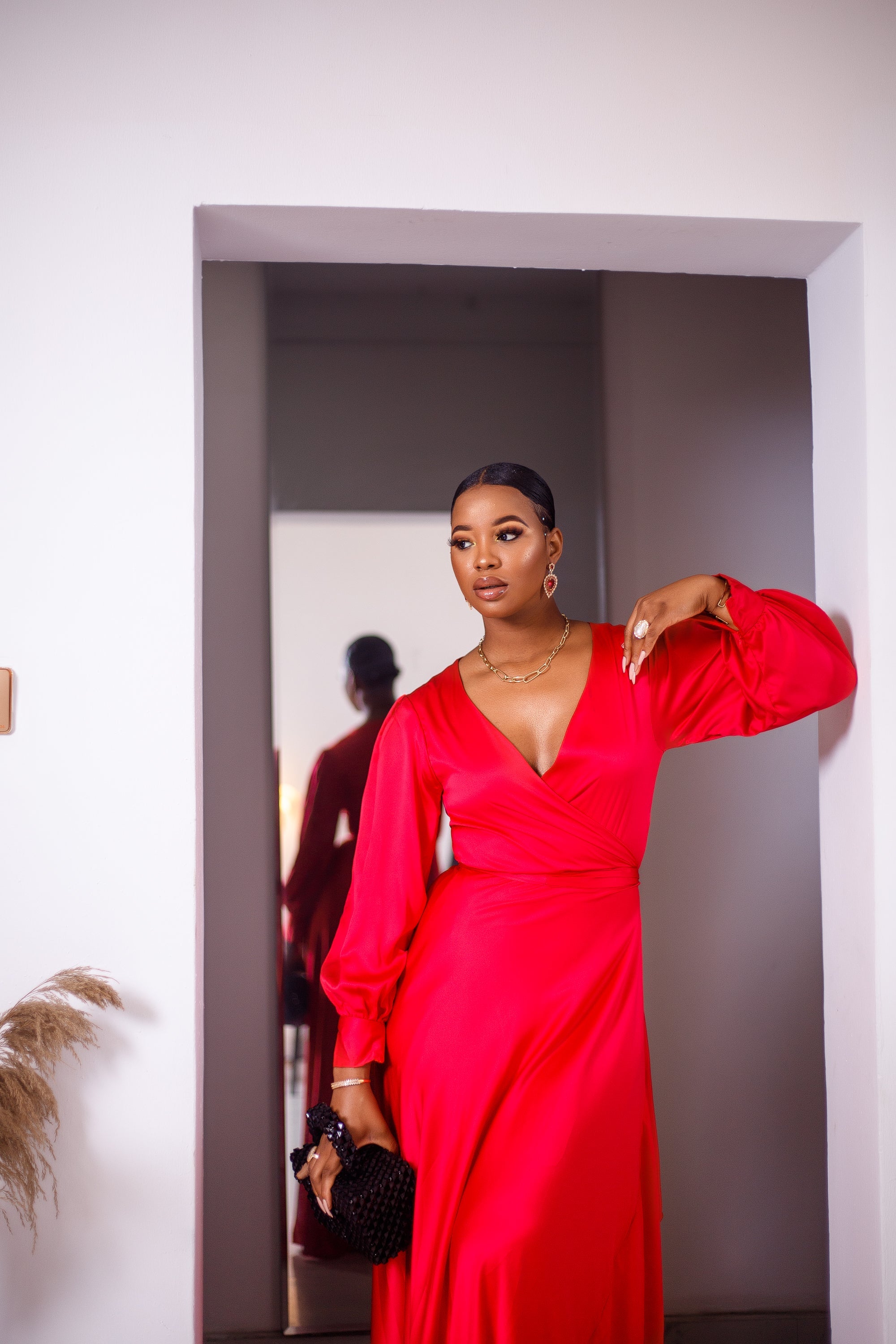 A woman posing in a red maxi dress with ruffles.