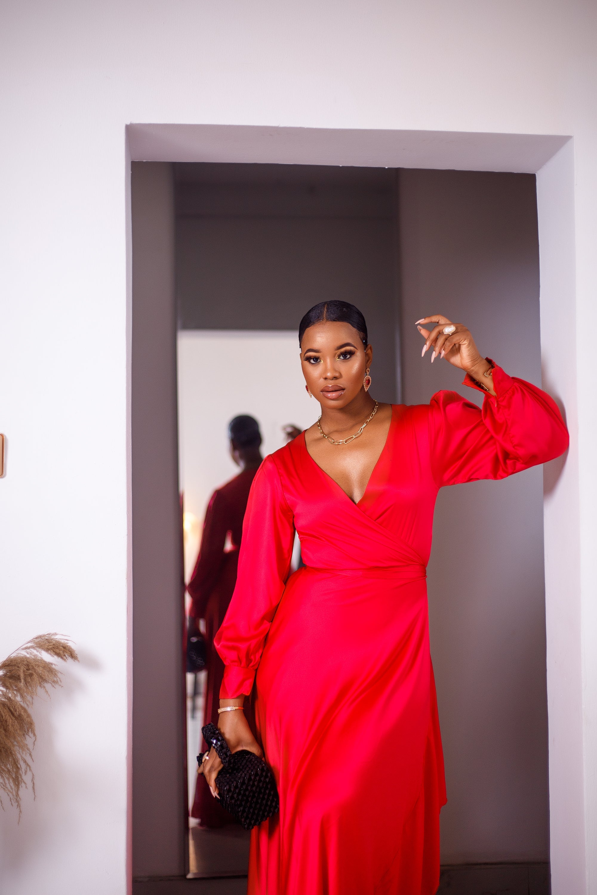 A woman posing in a red maxi dress with ruffles.
