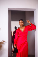 A woman posing in a red maxi dress with ruffles.