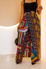 Model wearing a vibrant, multi-colored African Ankara pants and skirt with intricate patterns, featuring an elastic waistband and zipper closure.
