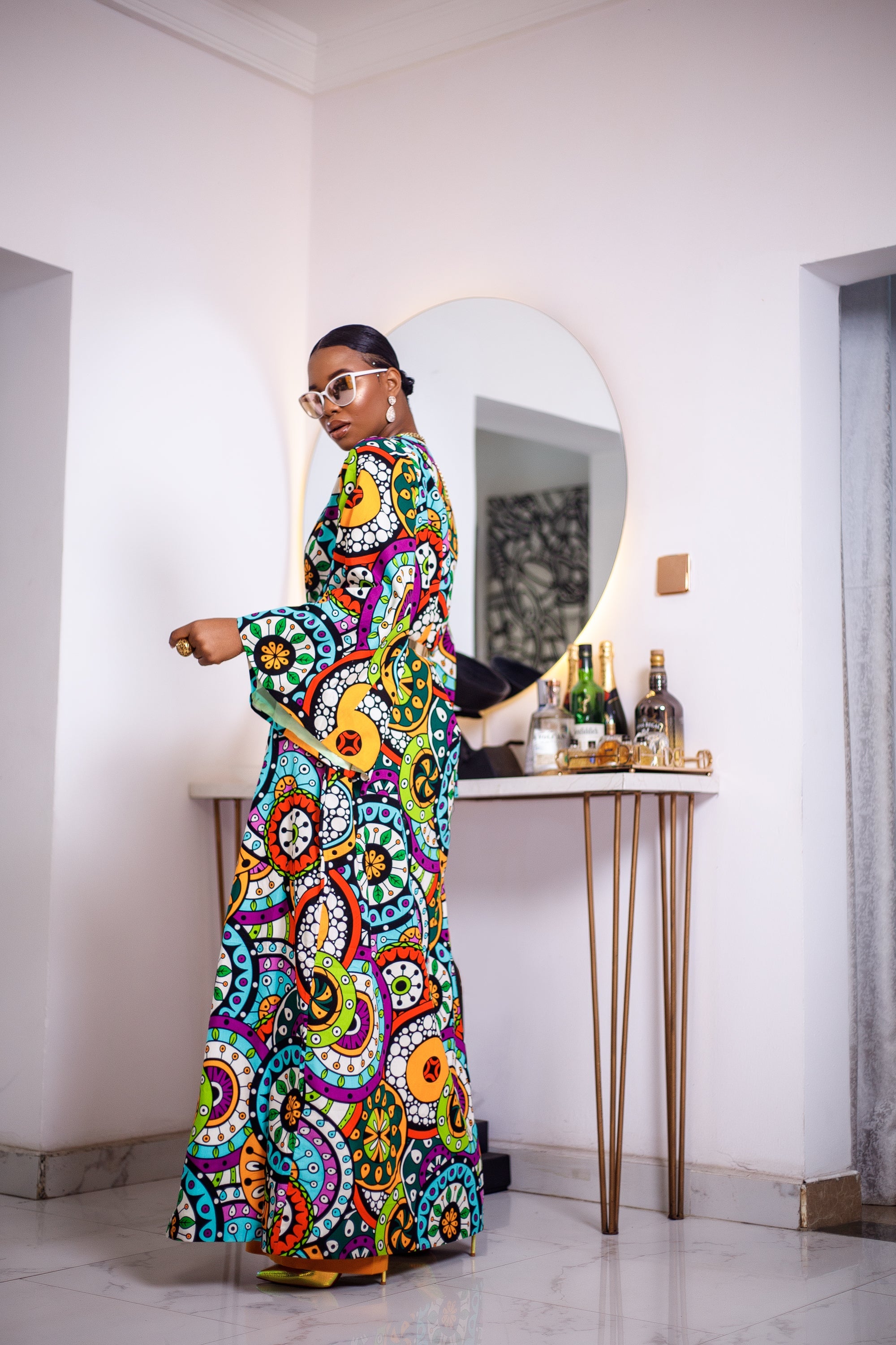 A woman posing in a multicolored African Print kimono.