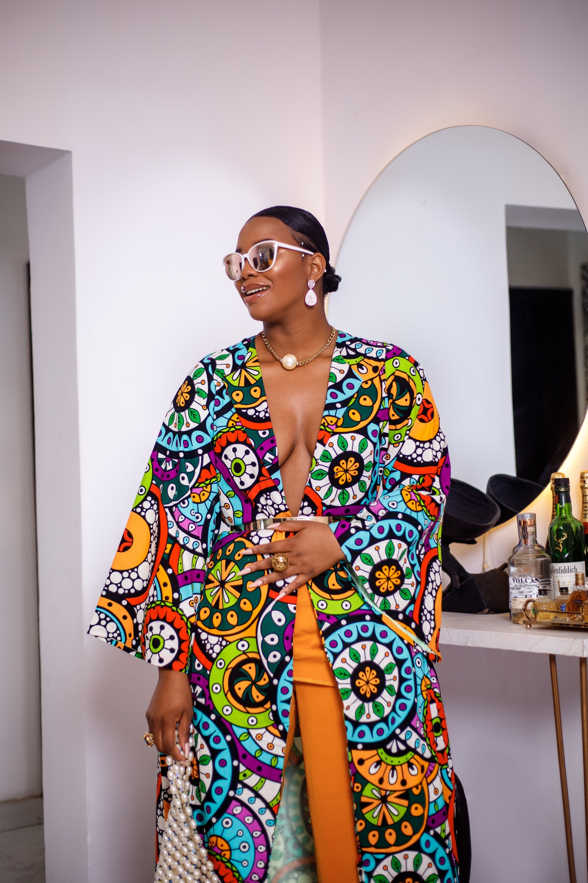 A woman posing in a multicolored African Print kimono.