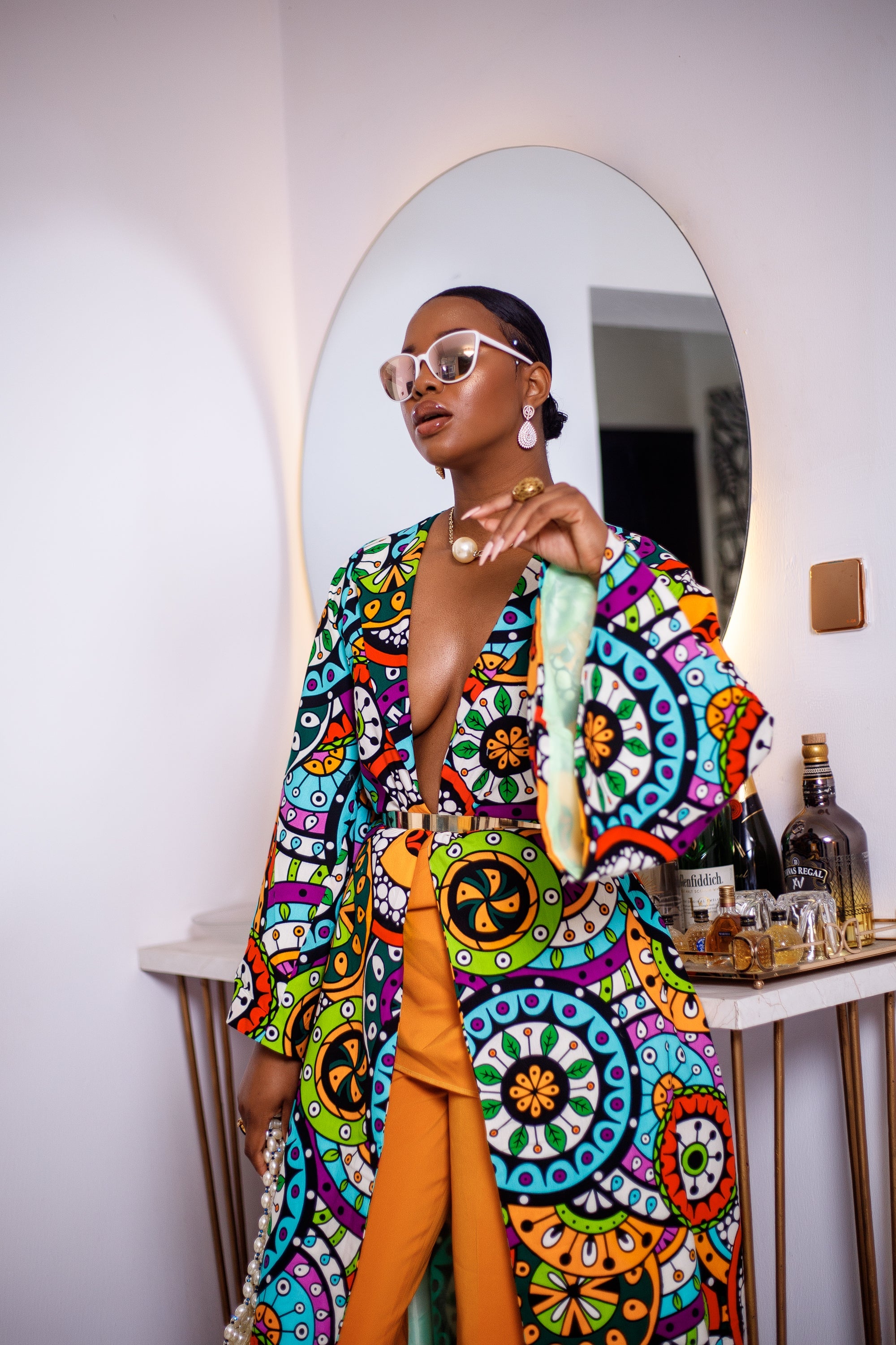 A woman posing in a multicolored African Print kimono.