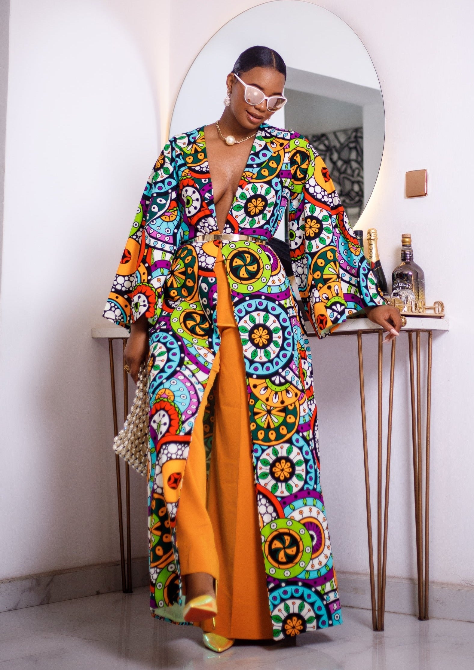 A woman posing in a multicolored African Print kimono.