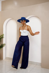 Woman wearing Umunya high-waist wide-leg navy jean pants with a white bustier top and blue hat