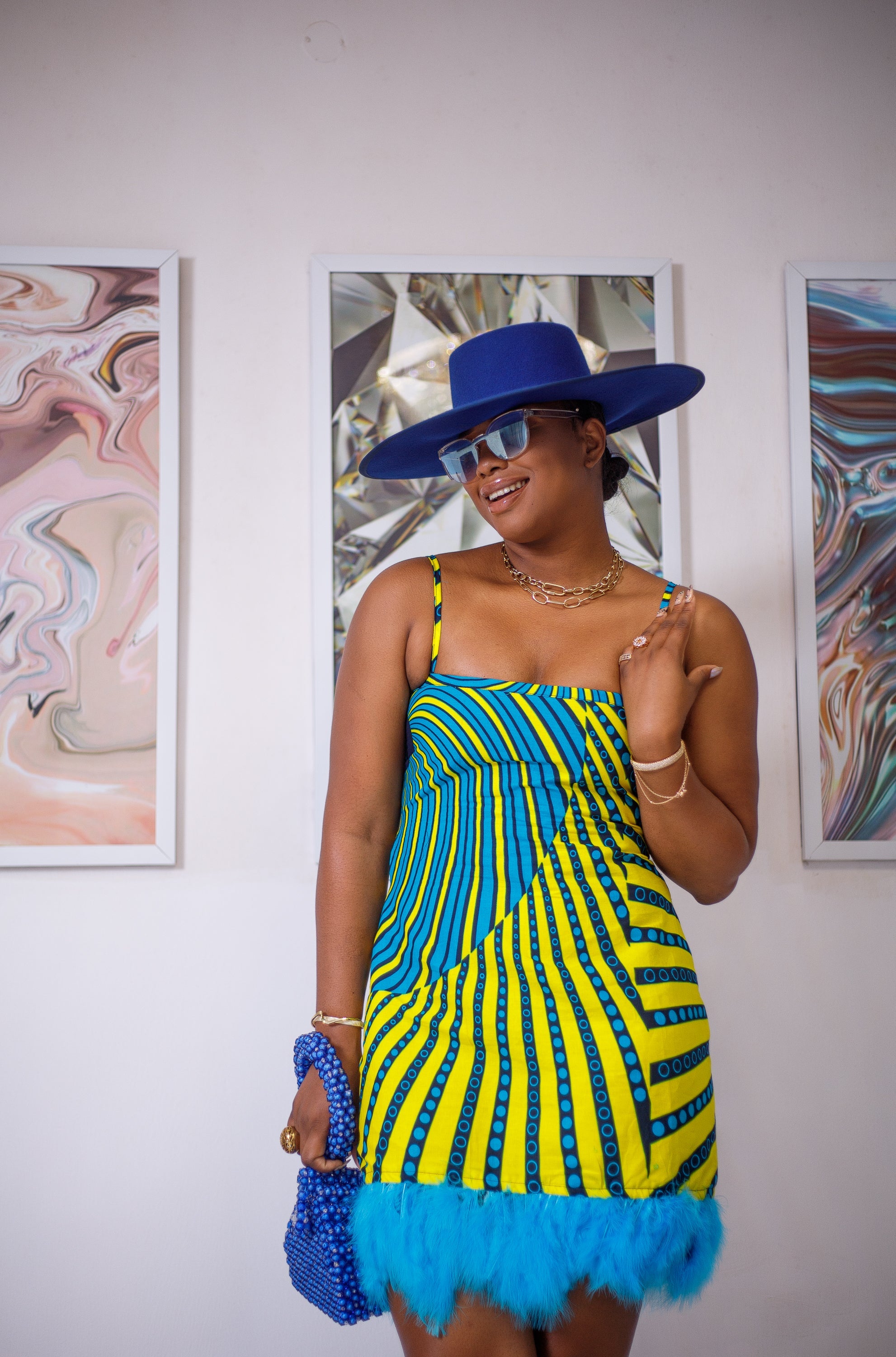 A woman posing in a blue and yellow African print mini dress.